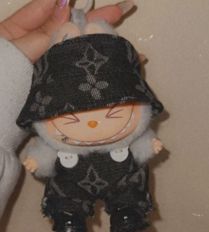 a girl wearing a hoodie has dressed the cute furry labubu doll grey in color in thrifted louis vuitton clothes 