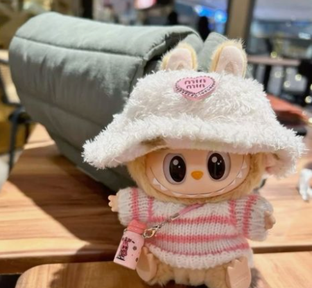 Cute Labubu doll with a furry white hat wearing a crochet pink sweater used as a keychain with a daily lifestyle purse